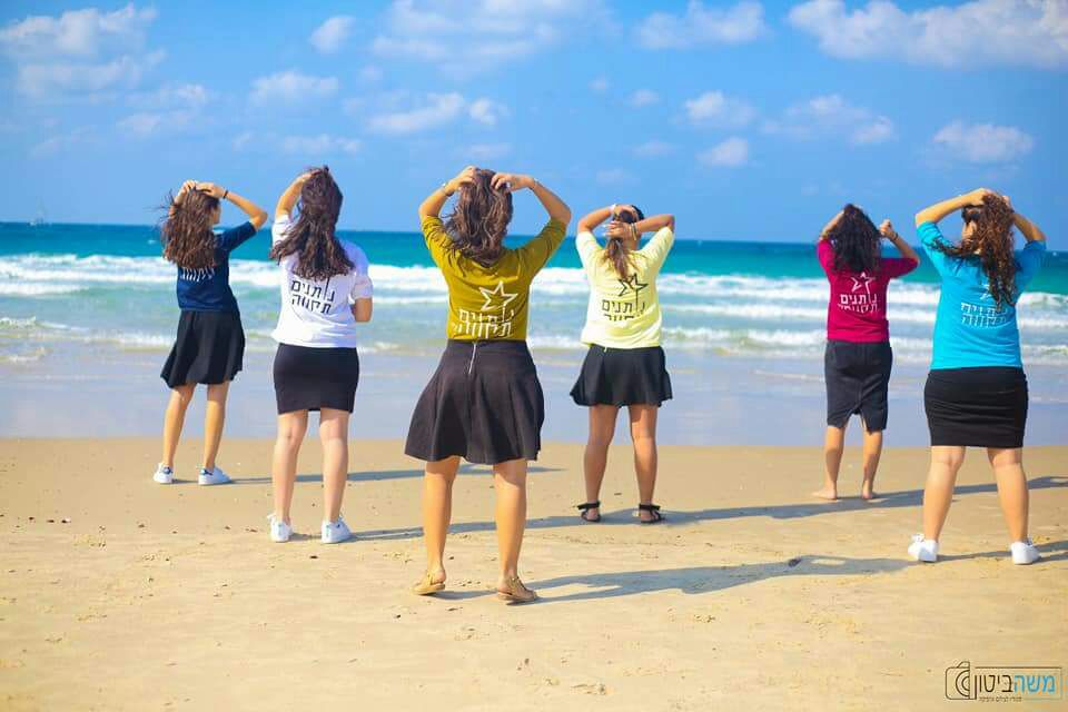 בנות השירות של נותנים תקווה בים עם חולצות של נותנים תקווה